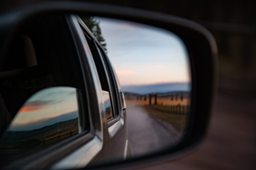 Car mirror looking back at landscape